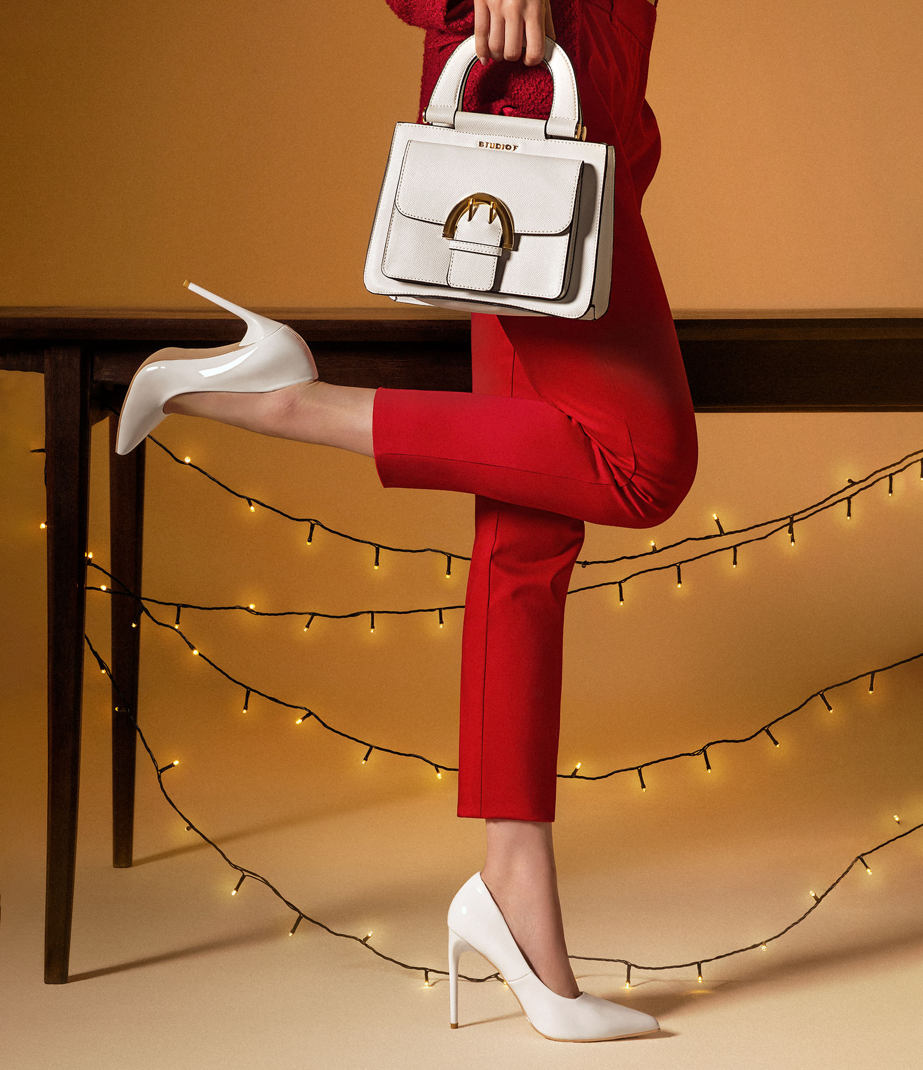 Pantalón rojo, zapatos cerrados blancos y bolso de mano con herraje dorado de la marca Studio F 