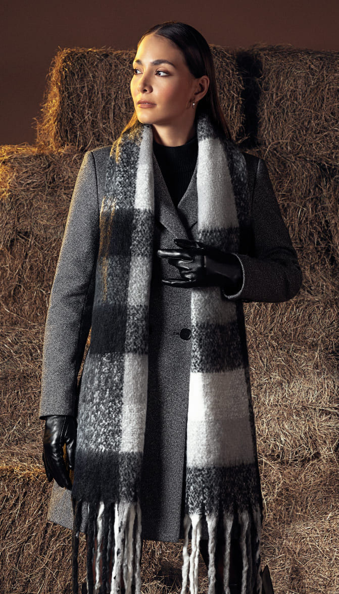 Mujer vistiendo gaban color gris, guantes negros y bufanda de franjas negro, gris y blanco de la marca Studio F