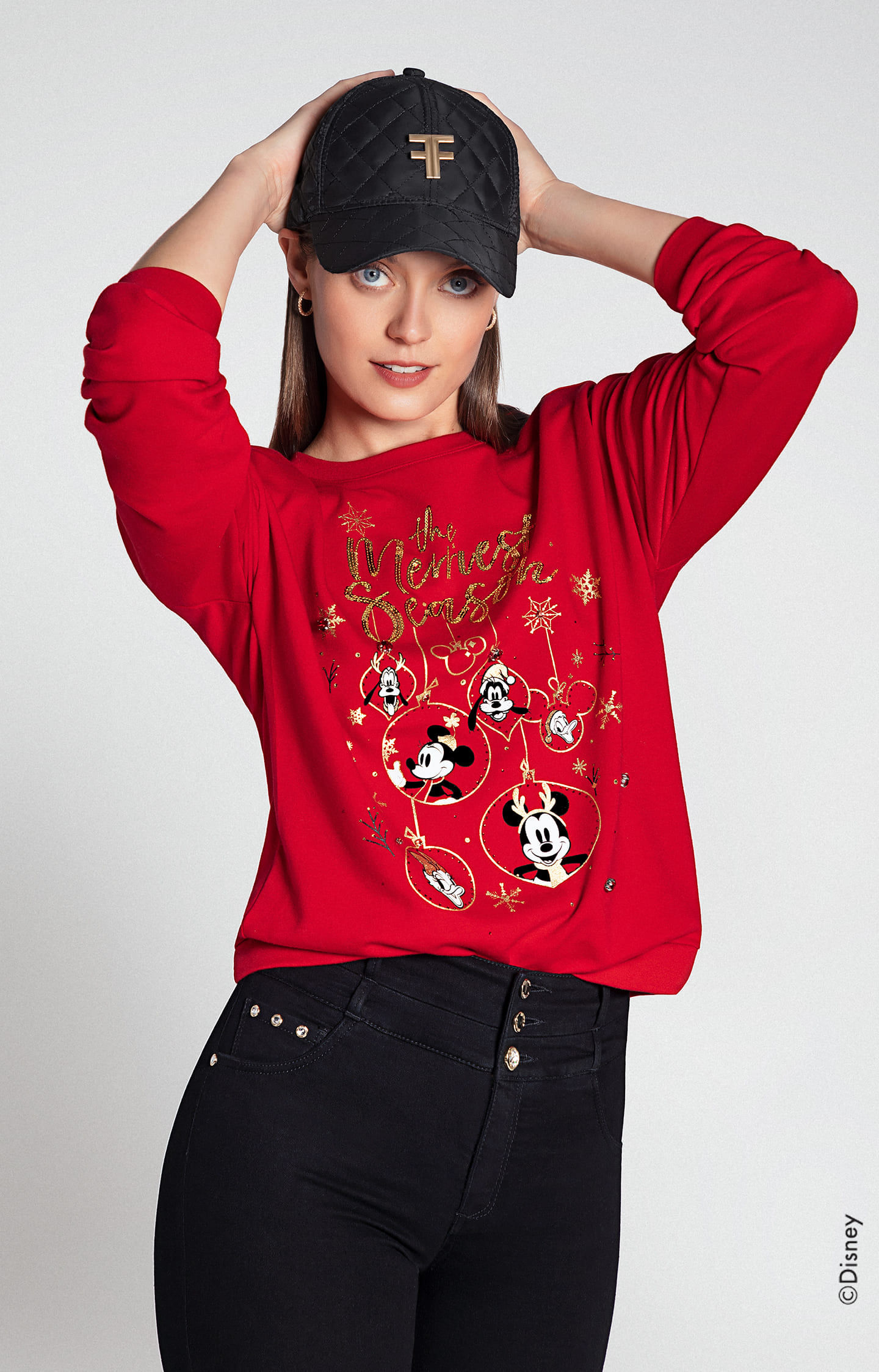 Mujer vistiendo buzo rojo de navidad con personajes de disney, pantalón negro y gorra negra studio F