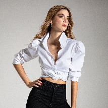 Foto de mujer con blusa blanca manga larga con nudo en el abdomen y jean ultra slim fit color negro de la marca Studio F 
