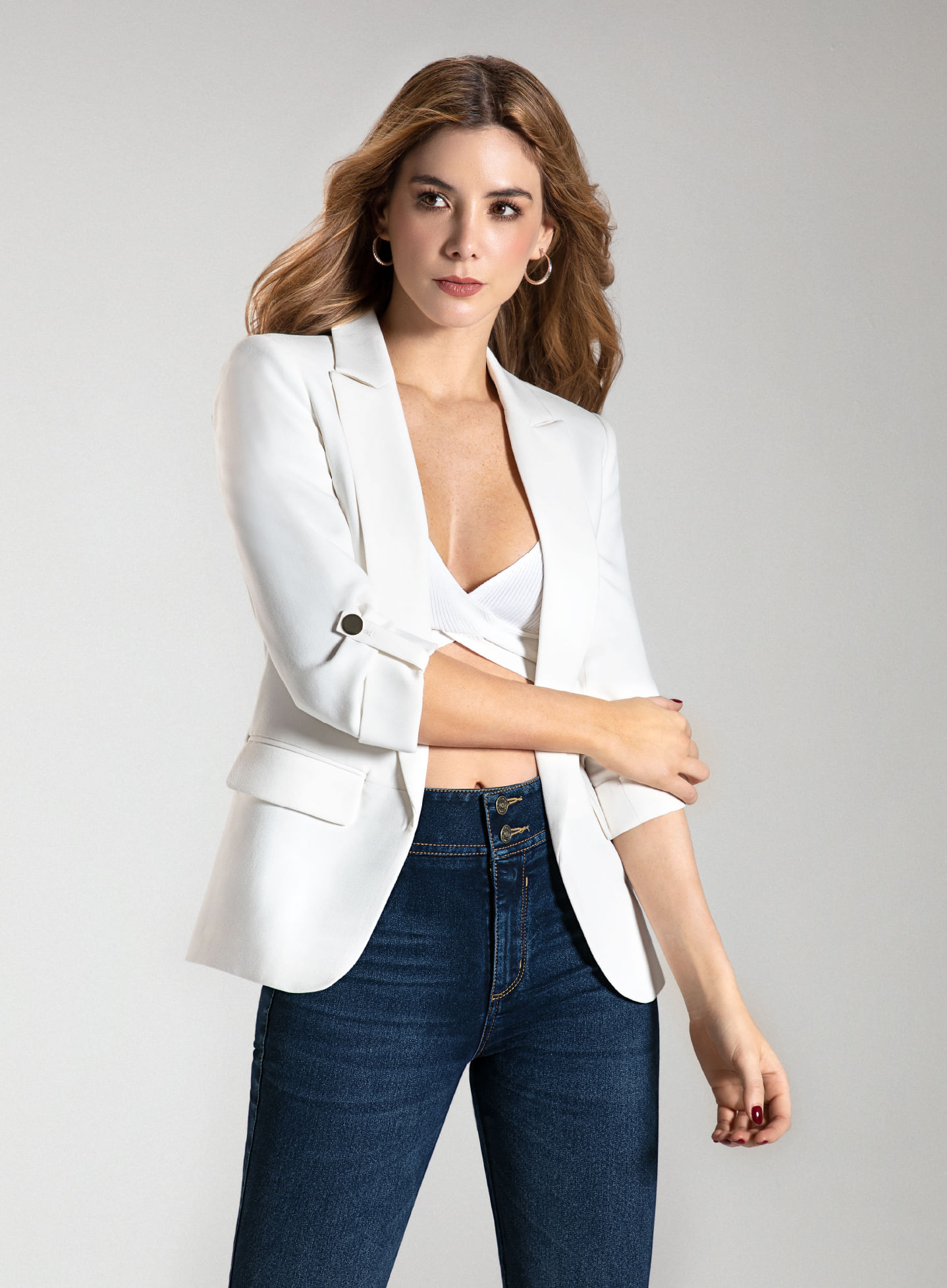 Foto en plano americano de mujer usando blazer blanco, crop top blanco cruzado y jean fit salma