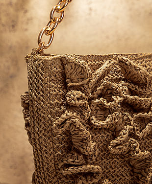 Foto en plano detalle de bolsa pequeña en fibras naturales color café con cadena dorada 