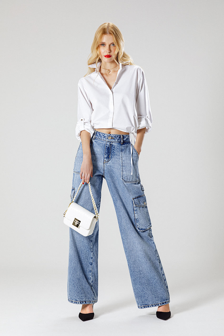 Foto de modelo usando blusa blanca, jean tipo cargo, bolsa de mano y zapatos cerrados color negro 